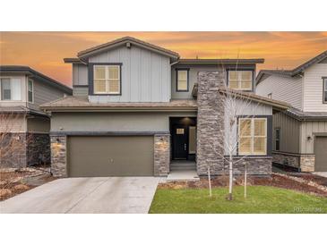 Two-story home boasts a stylish design with stone accents and a neutral color palette, set against a vibrant sunset sky at 533 Red Thistle Dr, Highlands Ranch, CO 80126