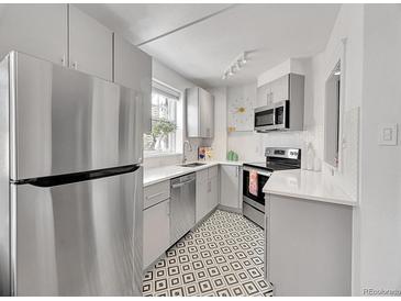 Modern kitchen with stainless steel appliances, bright countertops and a unique geometric tile floor at 215 E 11Th Ave # D8, Denver, CO 80203