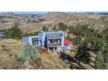Stunning view of the exterior of a mountainside home with a wood deck and views of the mountains and surrounding trees at 319 Camino Bosque, Boulder, CO 80302