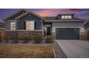 Charming home exterior featuring a stone facade, two-car garage, and manicured landscaping at 11346 Kittredge St, Commerce City, CO 80022
