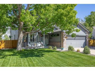 Charming gray home featuring a well-manicured lawn, inviting front porch, and mature shade tree at 11760 Eudora Ct, Thornton, CO 80233