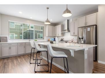 Bright, modern kitchen with stainless steel appliances, white cabinets, and a large center island with bar seating at 8953 Southurst St, Littleton, CO 80129