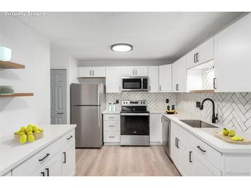 Bright kitchen with modern cabinets, stainless steel appliances, and stylish herringbone backsplash at 3470 S Poplar St # 401, Denver, CO 80224