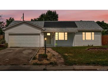 Charming ranch-style home featuring solar panels, attached garage, and well-lit entry, set against a beautiful sunset sky at 1670 Oakland St, Aurora, CO 80010
