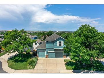 Aerial view of a blue two-story home with a three-car garage and lush landscaping at 12535 S Beaver Creek Way, Parker, CO 80134