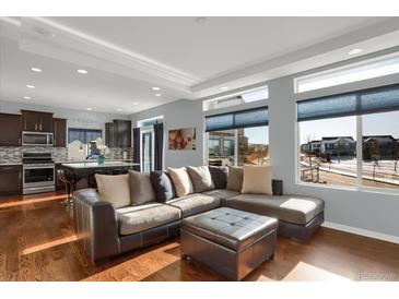Bright living room showcasing hardwood floors, a modern sectional couch, and an open concept kitchen at 17938 E 54Th Ave, Denver, CO 80249