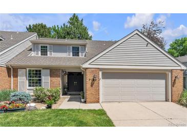 Charming home featuring a two-car garage, brick accents, lush greenery, and a well-manicured lawn, offering great curb appeal at 7183 S Poplar St, Centennial, CO 80112