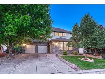 Charming two-story home with a stone facade, three-car garage, and well-maintained front yard with mature trees at 12350 Turquoise Terrace St, Castle Pines, CO 80108