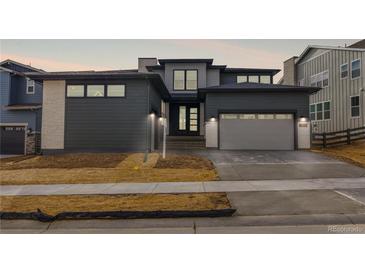 Modern two-story home featuring gray siding, stone accents, a two-car garage and professionally landscaped yard at 6529 Still Pine Cir, Castle Pines, CO 80108
