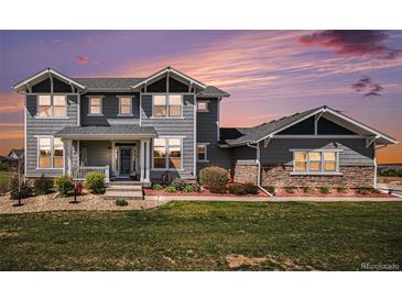 Charming two-story home with gray siding, stone accents, and a well-manicured lawn at dusk at 7692 Weaver Cir, Castle Rock, CO 80104