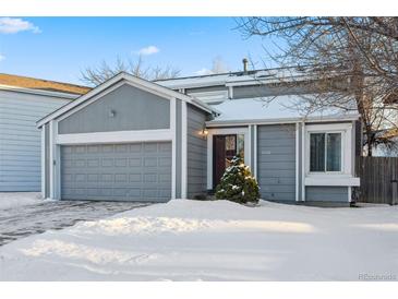 Snow-covered exterior of a charming two-story home with a gray facade and attached garage at 9292 W 98Th Way, Westminster, CO 80021