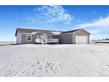 Ranch-style home with attached garage and deck, snow-covered yard at 9 Timberlake Ct, Byers, CO 80103