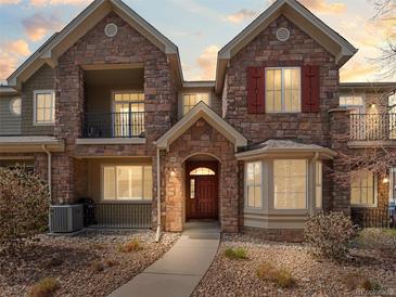 Charming stone townhome with a well-maintained front yard, covered balcony, and inviting front entrance at 15496 W 66Th Dr # B, Arvada, CO 80007