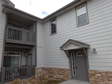 Two-story home featuring stone accents, gray siding, an entrance awning and balcony at 3271 E 103Rd Pl # 1308, Thornton, CO 80229