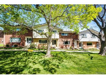 Charming townhomes featuring brick and siding, shaded by mature trees and a well-maintained green lawn at 12632 W Virginia Ave, Lakewood, CO 80228