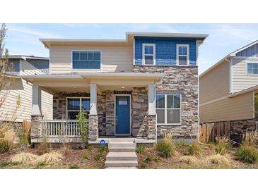 Two-story home featuring a stone facade, inviting front porch, and attractive blue door at 868 N Quatar St, Aurora, CO 80018
