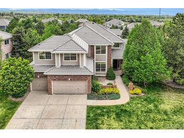 Charming two-story home with manicured lawn, mature trees, and a brick-accented, two-car garage at 10529 Dacre Pl, Lone Tree, CO 80124