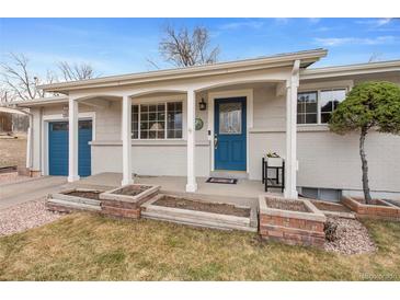 Charming single-story home with a beautiful blue front door, brick planters, and well-maintained landscaping at 1359 Chambers Rd, Aurora, CO 80011