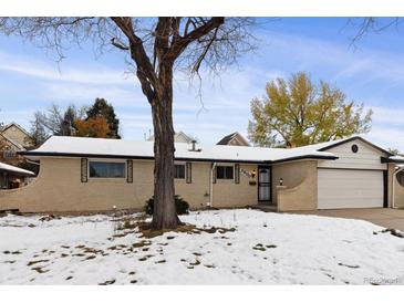 Inviting one-story home featuring a brick facade, attached garage, and a charming front yard at 5800 W Warren Ave, Denver, CO 80227