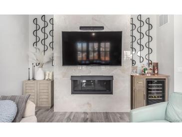 Stylish living room featuring a modern fireplace, TV, and sleek cabinetry with a small wet bar at 10524 Eby Cir, Lone Tree, CO 80124