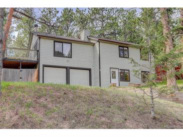 Two story home with attached 2 car garage, upper deck and situated amongst mature trees at 29762 Spruce Rd, Evergreen, CO 80439