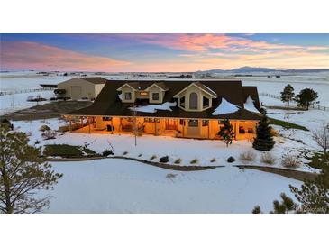 Charming home featuring a covered porch, large windows, and a snow-covered landscape at 4075 Merada Ct, Franktown, CO 80116