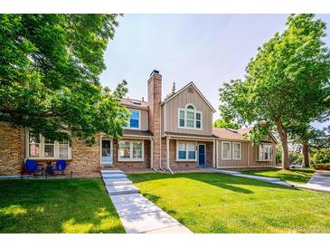 Charming townhome featuring a well-maintained lawn, brick accents, and a welcoming entrance at 9621 W Chatfield Ave # F, Littleton, CO 80128
