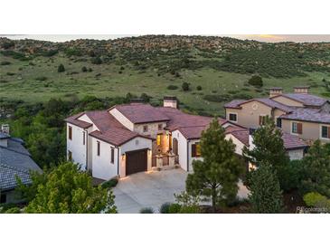 Stunning home exterior with tile roof, stone accents, three-car garage, and landscaped yard at 8278 Raphael Ln, Littleton, CO 80125