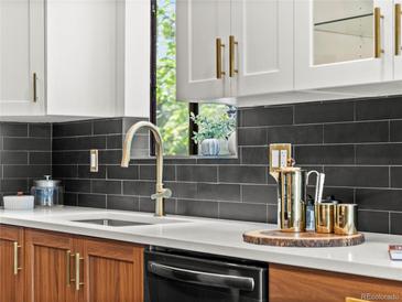 Modern kitchen featuring a stainless steel faucet, black backsplash, and stylish countertop decor with white and wood cabinets at 3001 S Ursula Cir # 101, Aurora, CO 80014