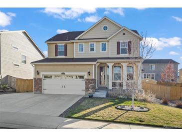 Charming two-story home with well-maintained lawn, a two car garage and covered porch on a sunny day at 14275 Grape St, Thornton, CO 80602