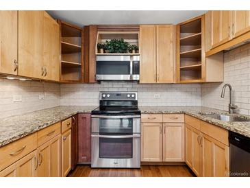Bright kitchen features wood cabinets, granite countertops, stainless steel appliances, and stylish subway tile backsplash at 655 S Alton Way # 6A, Denver, CO 80247