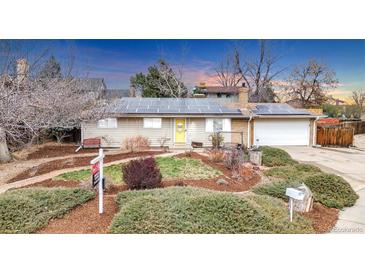 Charming single-story home with a manicured front yard, solar panels, and a yellow front door at 7727 W 81St Pl, Arvada, CO 80005