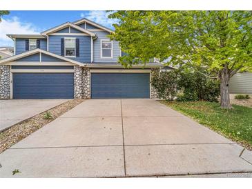Charming two-story townhouse featuring a blue facade, stone accents, and a spacious driveway for convenient parking at 6110 Raleigh Cir, Castle Rock, CO 80104