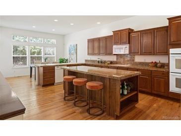 A kitchen featuring wood cabinets, granite counters and island with seating at 12447 W 77Th Ave, Arvada, CO 80005