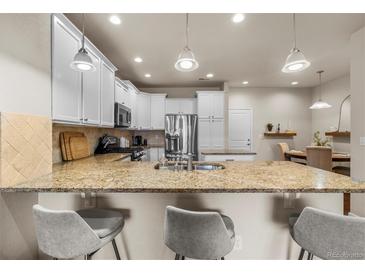 Bright kitchen features granite countertops, stainless steel appliances and a breakfast bar at 9071 E Phillips Dr, Centennial, CO 80112