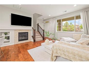 Inviting living room with fireplace, wood floors, and large window at 9071 E Phillips Dr, Centennial, CO 80112