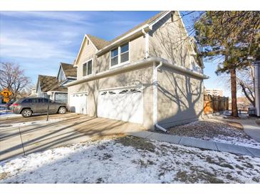 Tan three-car garage home with snow-covered yard at 7861 W 90Th Dr, Broomfield, CO 80021