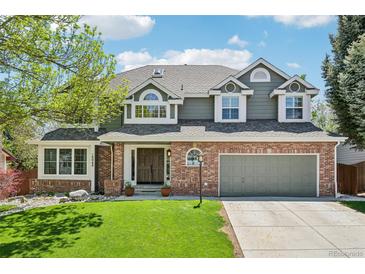 Charming two-story home featuring a brick facade, lush lawn, mature landscaping, and attached two car garage at 10068 Granite Hill Dr, Parker, CO 80134