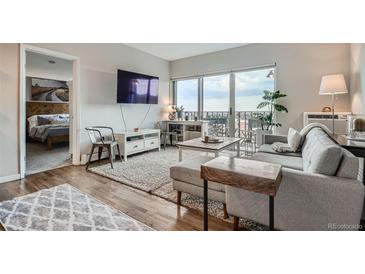 Bright living room with modern furniture, hardwood floors, and access to a balcony with great city views at 1150 Vine St # 1006, Denver, CO 80206