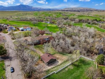 Expansive aerial view showcasing a sprawling home near a lush golf course and scenic mountain backdrop at 11489 W Bear Creek Dr, Lakewood, CO 80227