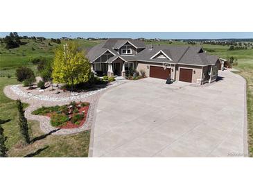 Sprawling home featuring a circular driveway, and a well-manicured lawn with mature trees and landscaping at 960 Promontory Cir, Elizabeth, CO 80107