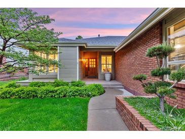 Charming front entrance with a wooden door, brick accents, and lush landscaping at 13 Pinyon Pine Rd, Littleton, CO 80127