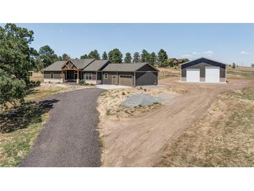 Expansive ranch-style home with a large garage/workshop on a spacious lot with a long driveway and mature trees at 5917 Black Forest Dr, Elizabeth, CO 80107