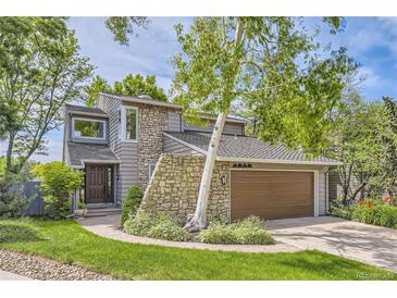 Charming home exterior with stone accents, a manicured lawn, and lush landscaping at 1540 W Briarwood Ave, Littleton, CO 80120
