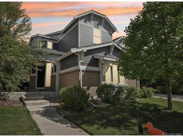 Inviting two-story home with gray siding, brick accents, and manicured landscaping in a desirable neighborhood at sunset at 25548 E Fair Dr, Aurora, CO 80016