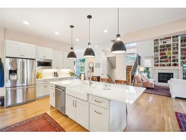 Bright kitchen with stainless steel appliances, white cabinets, and large island with pendant lighting at 1455 Flowers Ct, Erie, CO 80516