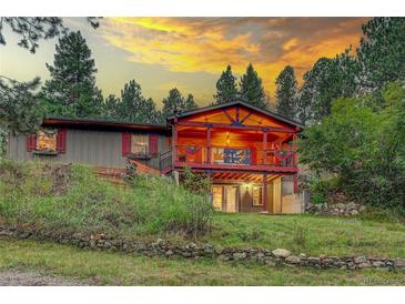 Charming home featuring a spacious deck, beautiful sunset views, and lush surrounding greenery at 29832 Dorothy Rd, Evergreen, CO 80439