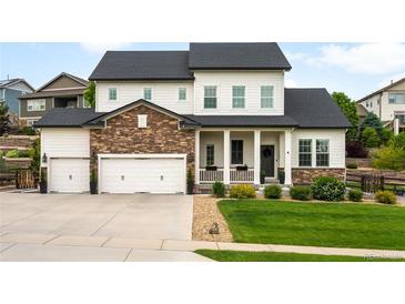 Charming two-story home featuring a manicured lawn, stone accents, and a three-car garage at 23421 E Rockinghorse Pkwy, Aurora, CO 80016