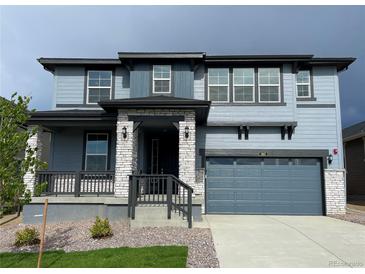 Charming two-story home featuring a covered porch, two-car garage, and stylish blue siding at 767 Raindance St, Erie, CO 80516