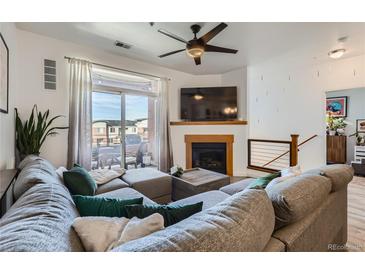 Bright living room featuring a modern fireplace, plush sectional sofa, and balcony access at 4100 Albion St # 221, Denver, CO 80216